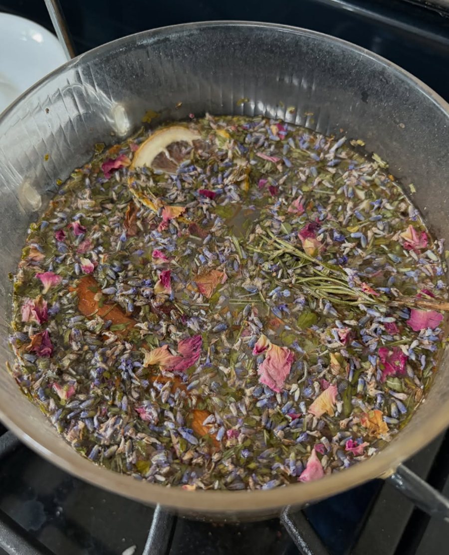 The Self Love kit simmering in a glass pot, with lemon, lavender and rose petals